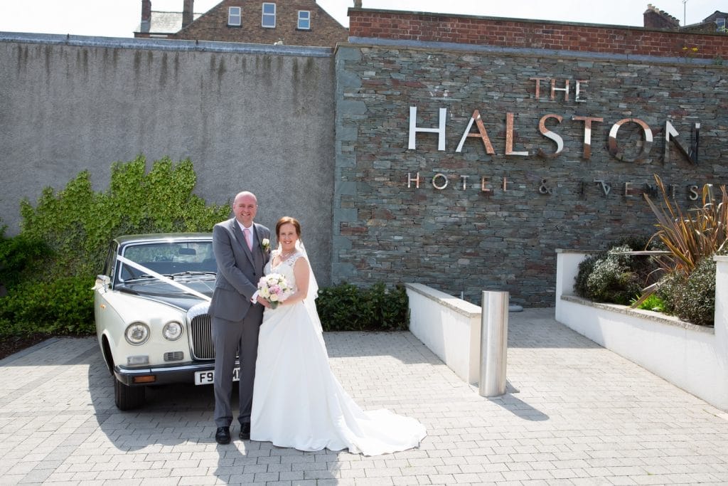 Bride and groom pose for photo outside The Halston, Carlisle