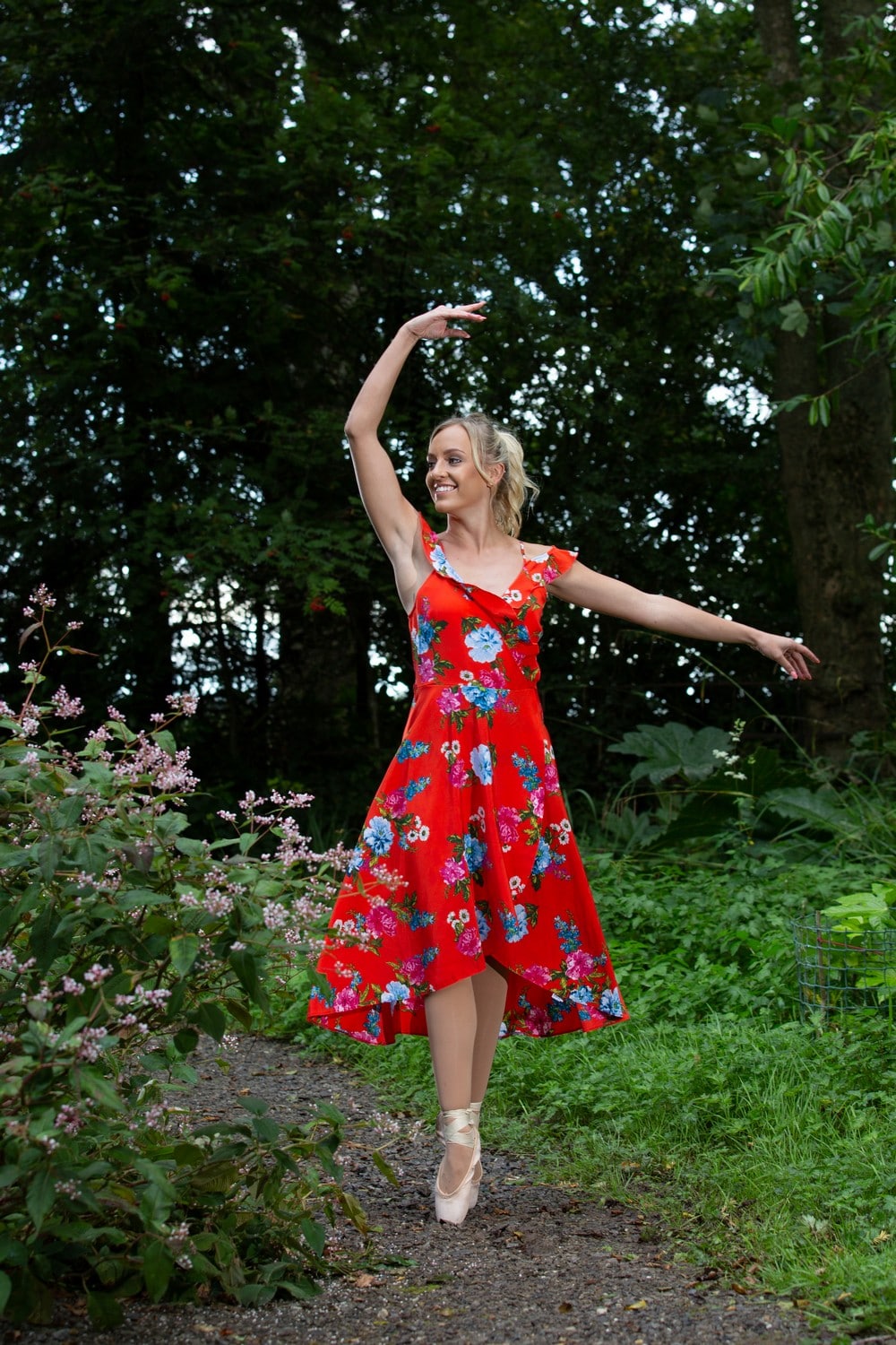 Ballet dancer on pointe in a red dress outside in the cumbrian countryside