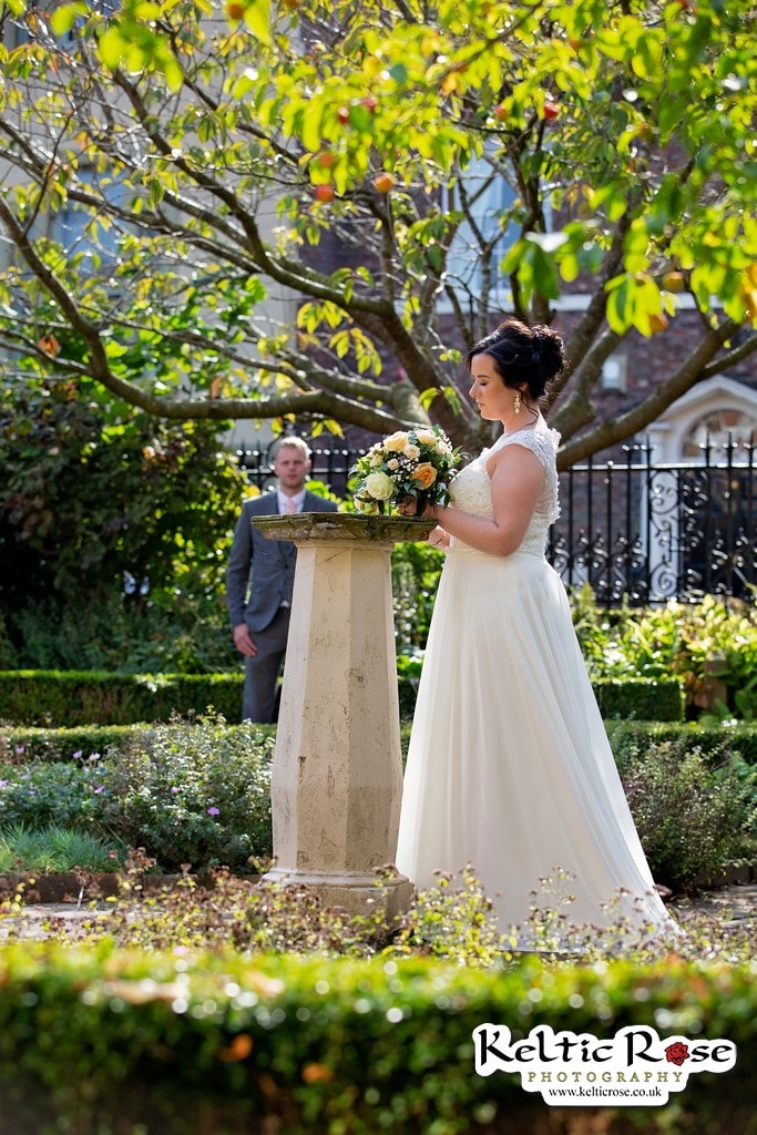 Bride at the Sundial at Tullie House Museum and Art Gallery with Groom in the background