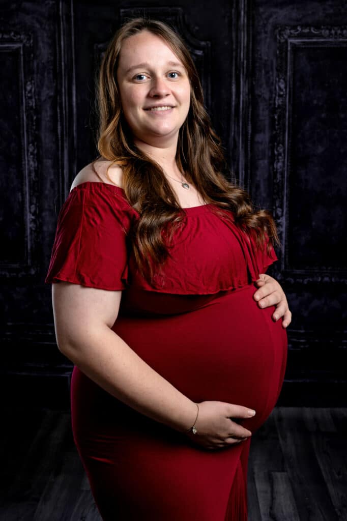 Maternity Photo of a pregnant lady in a red dress, holding her baby bump